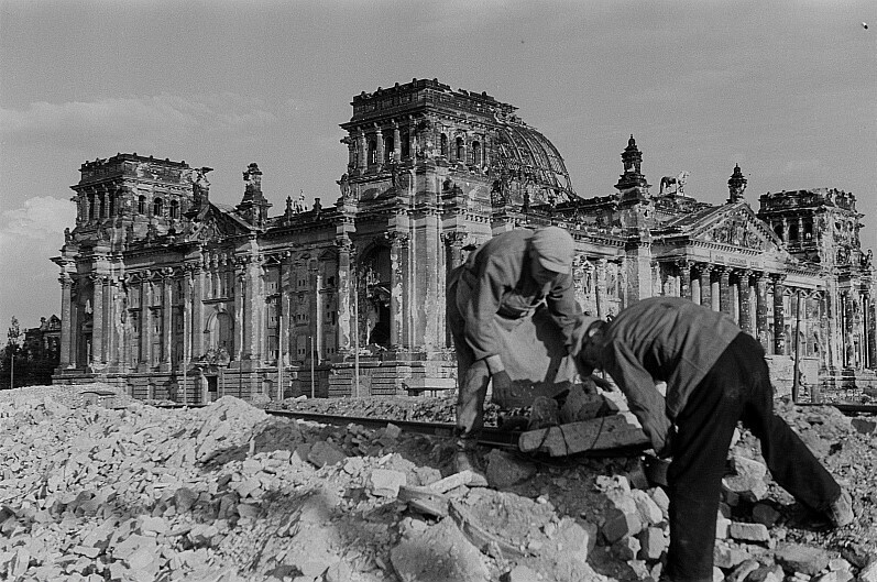 zwei Männer, die Trümmer vor dem Reichstag wegräumen
